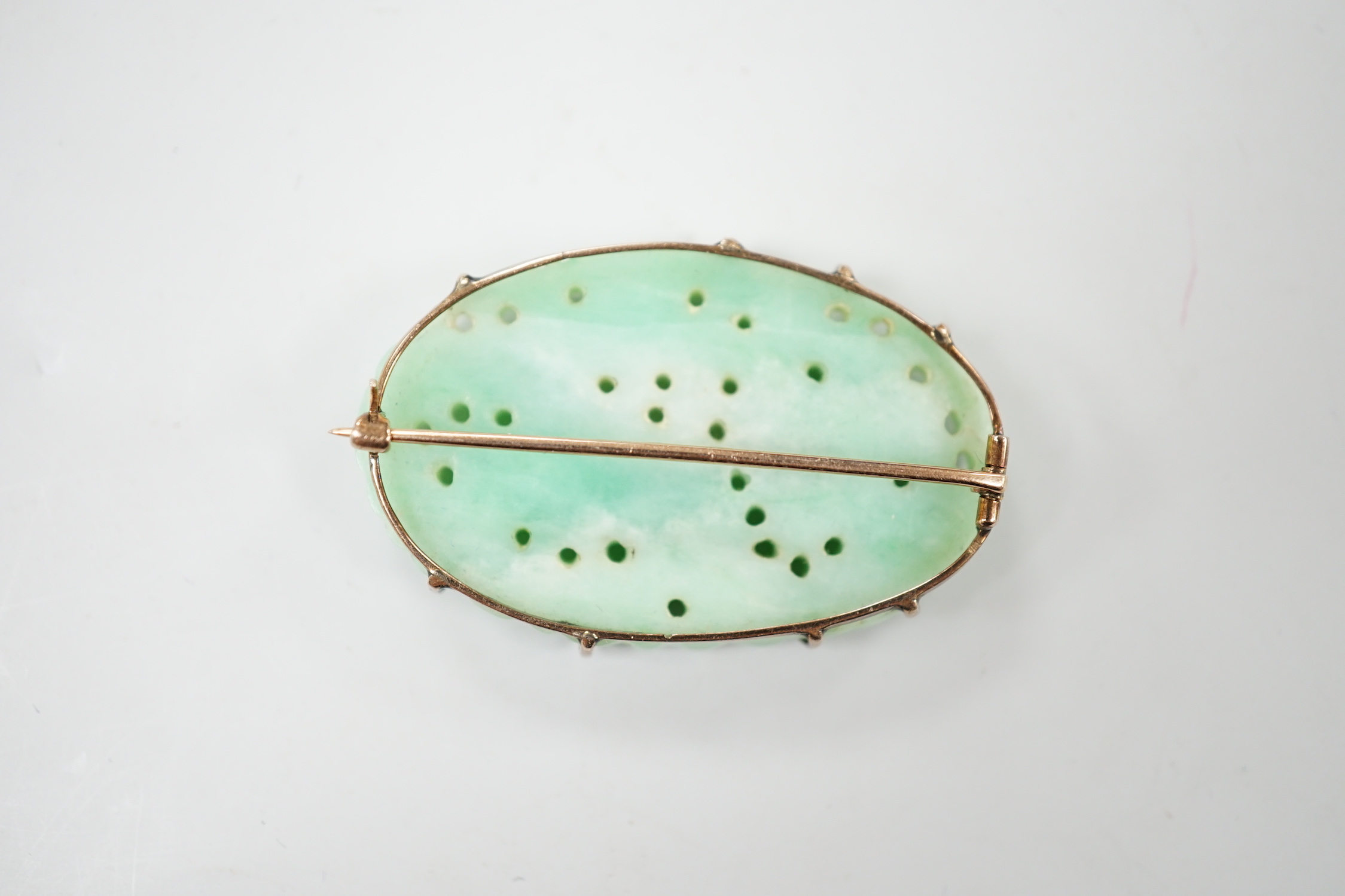 A Chinese yellow metal mounted carved jade oval brooch, 43mm, gross weight 15.8 grams